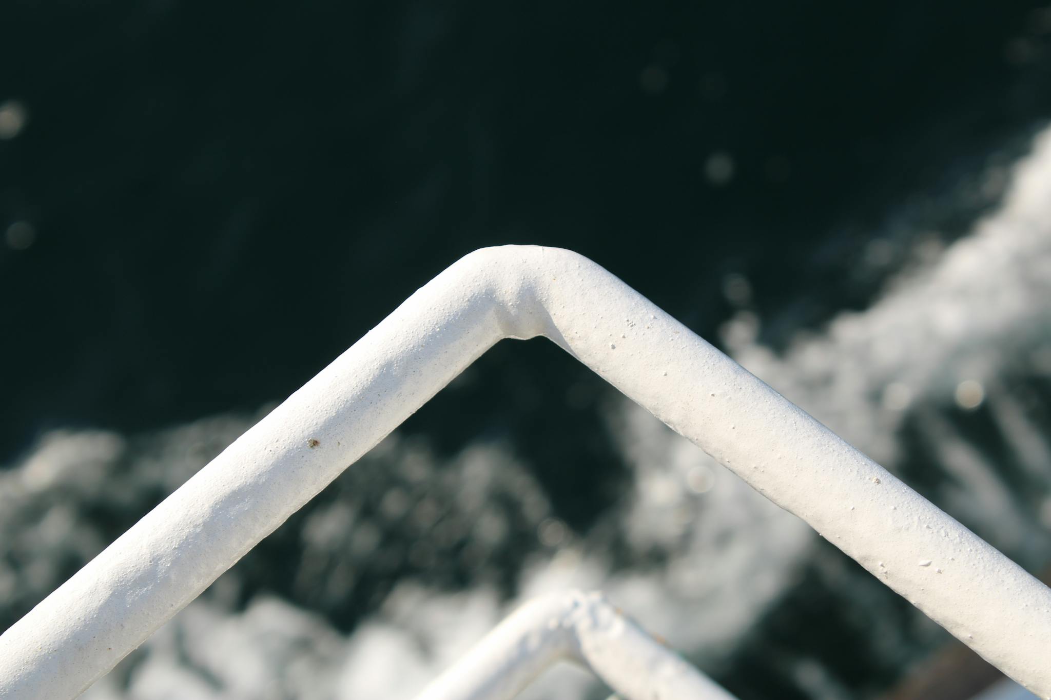 A close-up view of white metal railings with water in the background, showcasing industrial design.